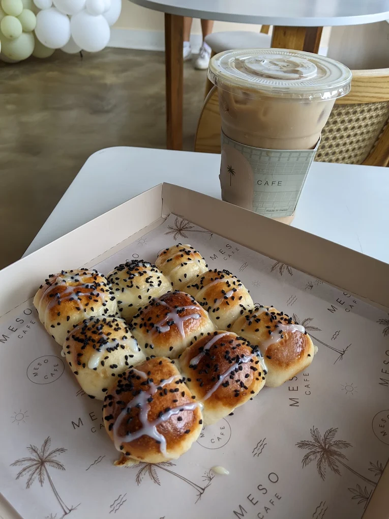 A box of sesame rolls and an iced latte on a table